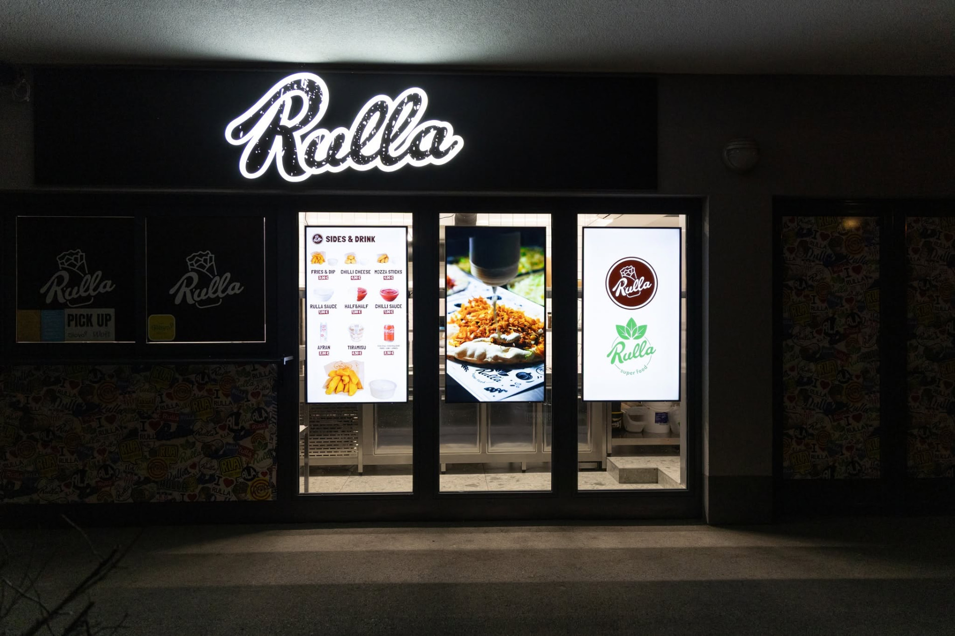 Rulla lokal noću s osvijetljenim logom i digitalnim menijem